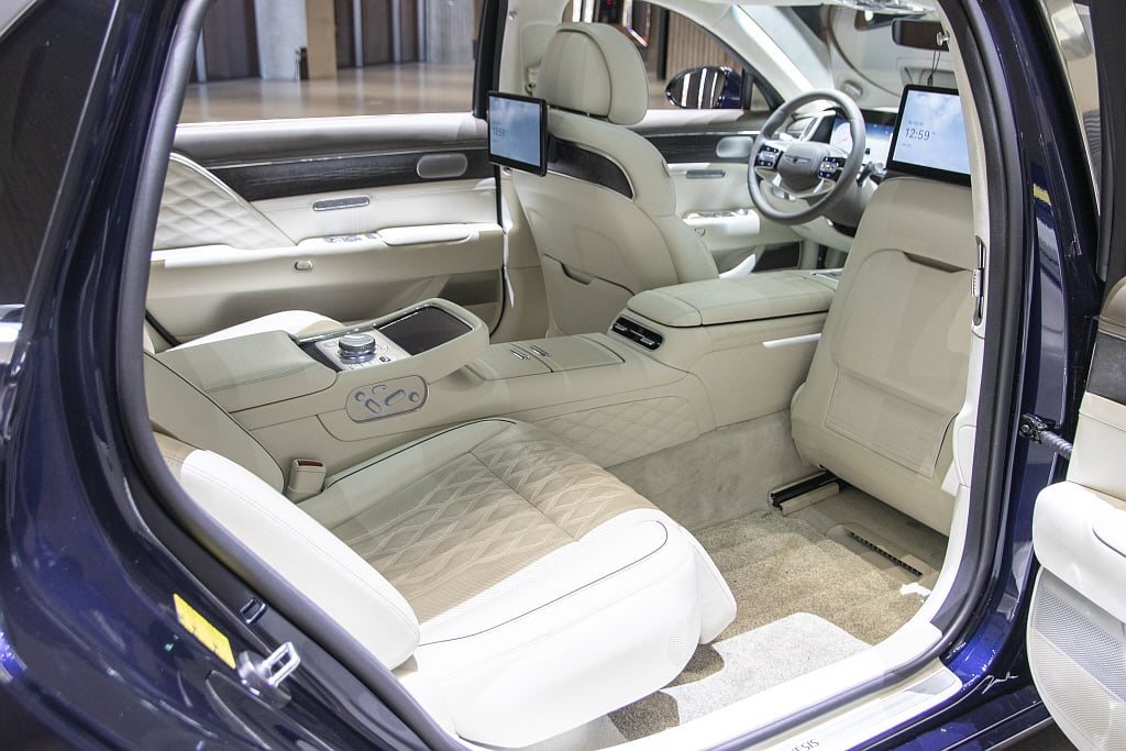Rear seats of a Genesis G90 sedan with reclining seat and screens